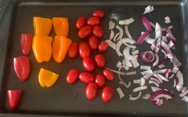 Cooking sheet with mini peppers, tomatoes, shallots and red onions